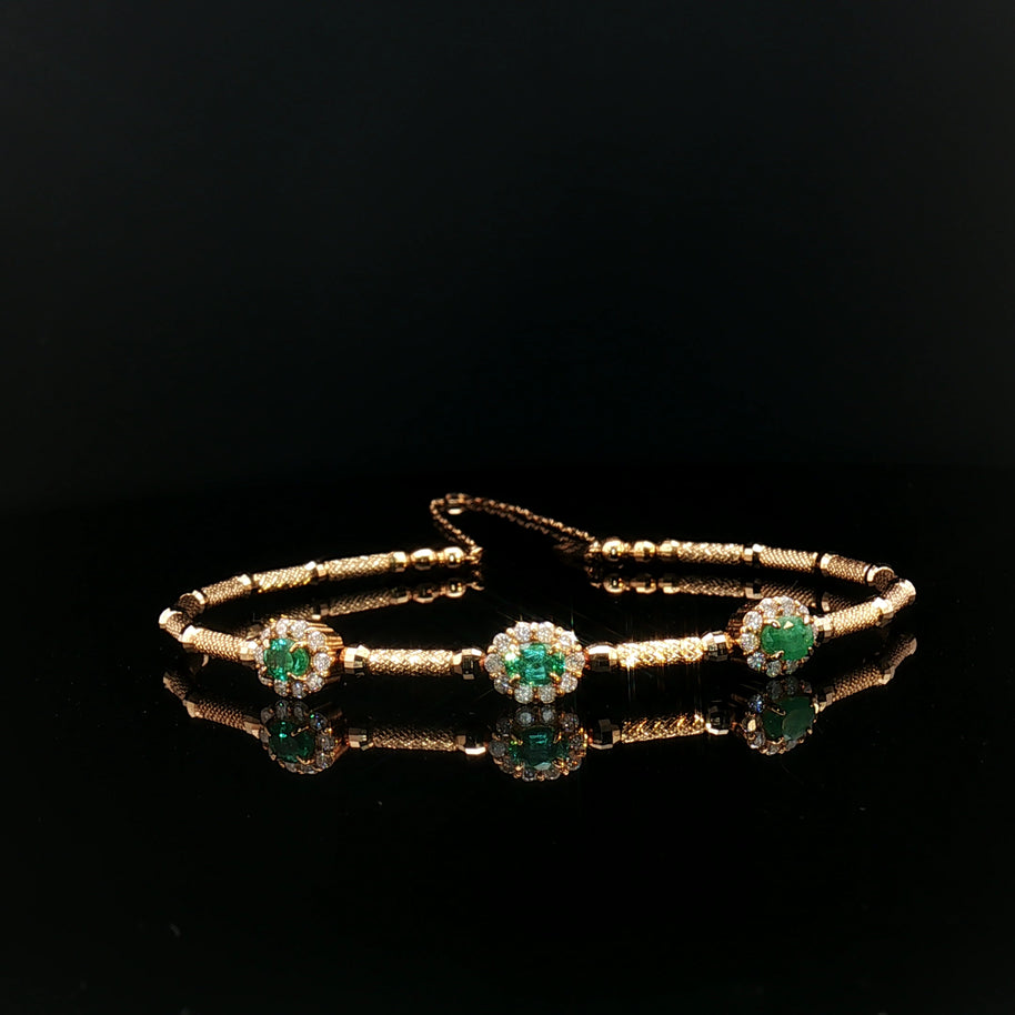 Gold bracelet with emerald green gemstones.