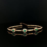 Gold bracelet with emerald green gemstones.