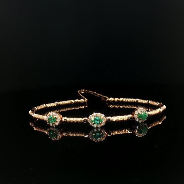 Gold bracelet with emerald green gemstones.