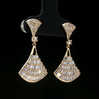 Close-up of fan-shaped gold earrings featuring brilliant round and baguette-cut diamonds
