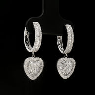 Close-up of heart-shaped white gold earrings featuring round and baguette-cut diamonds